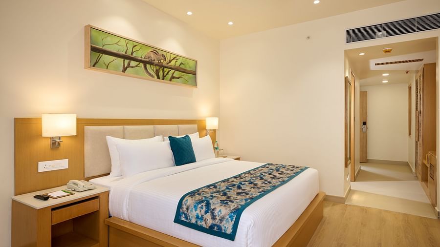 view of the double bed and entryway of the Deluxe room at ABN Sarovar Portico, Jim Corbett