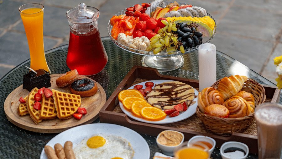 An image of a dining table showcasing beverages, fruits, snacks, and baked goods.