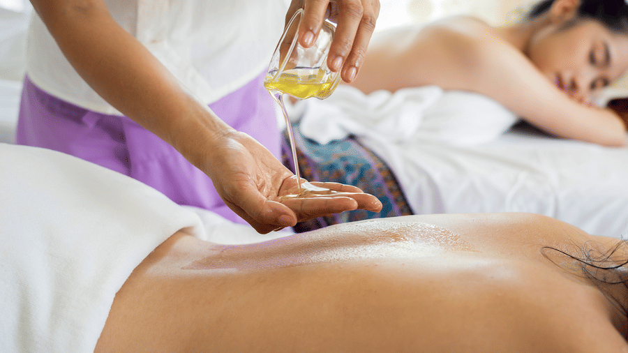 Two women at a spa getting massages by another woman.