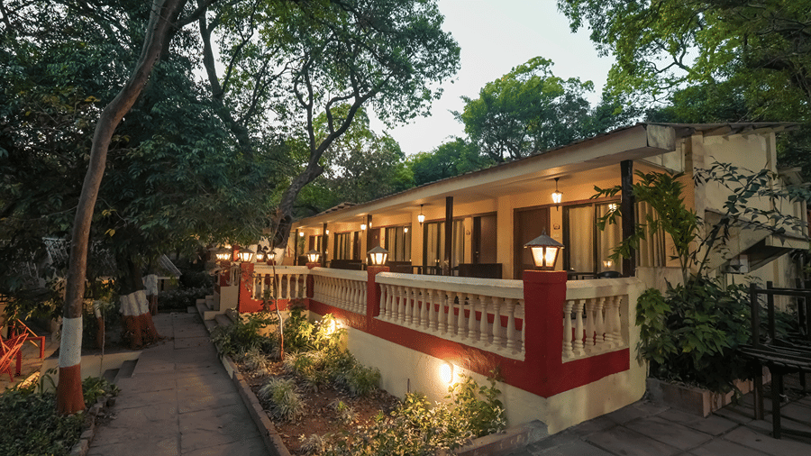 Exterior view of a resort property at dusk with warm lighting illuminating the pathways, garden, and building balconies.