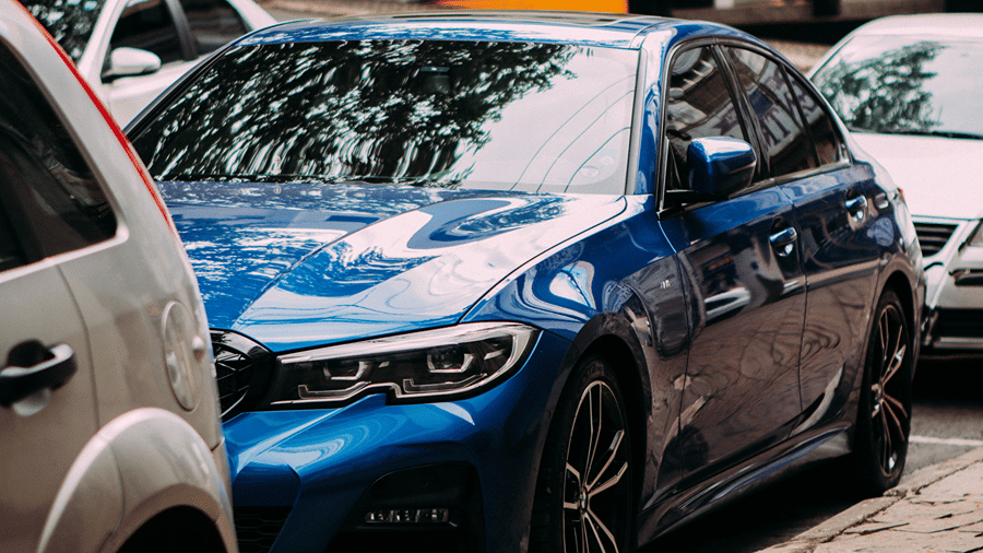 Modern blue sedan car parked in an outdoor lot, representing car rental and valet parking services.