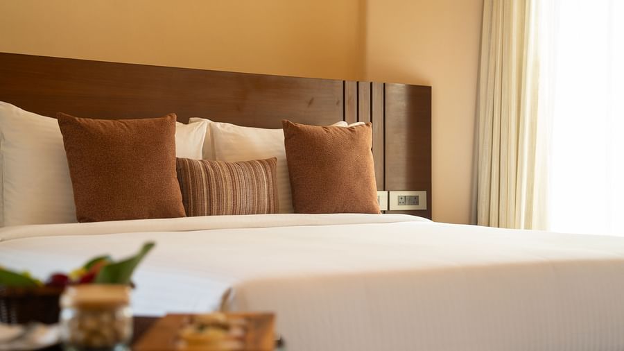 Elegant bedroom side view with layered pillows, bedside lighting, and a tray of refreshments at Ananta Spa and Resort, Ajabgarh.