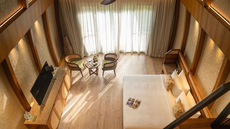 A stunning kind size bedroom with high ceilings, seating area, and large windows allowing natural light at Ananta Spa and Resort, Ajabgarh.