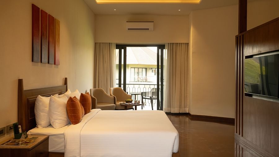 Side view of a spacious bedroom with wooden flooring, modern furniture, and balcony access at Ananta Spa and Resort, Ajabgarh.