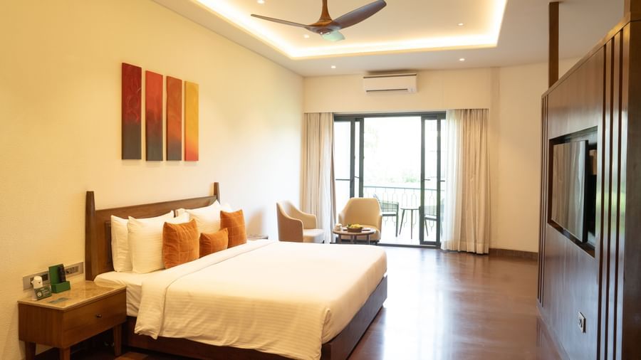 Spacious bedroom with wooden flooring, modern decor, and large glass doors opening to a sit-out at Ananta Spa and Resort, Ajabgarh.