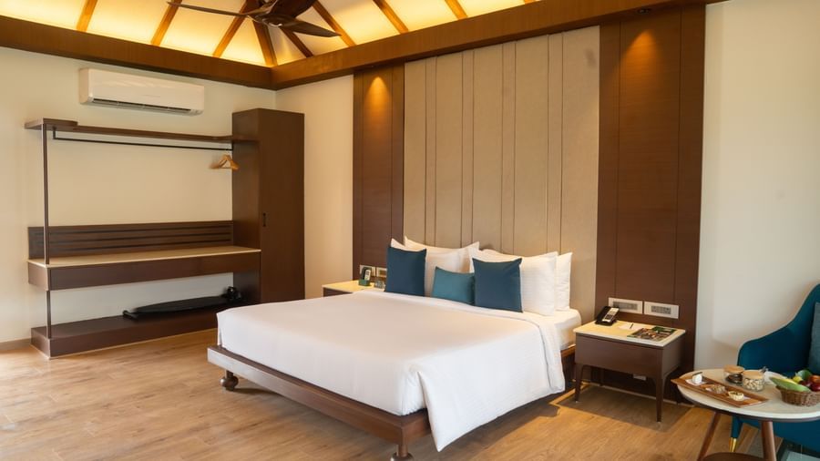 A King-size bed room with ceiling fan, wall-mounted air conditioner, sitting area, storage unit, and bed-side table at Ananta Spa and Resort, Ajabgarh.