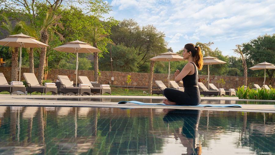 A woman practising breathing exercise near the pool at Ananta Spa and Resort, Ajabgarh 