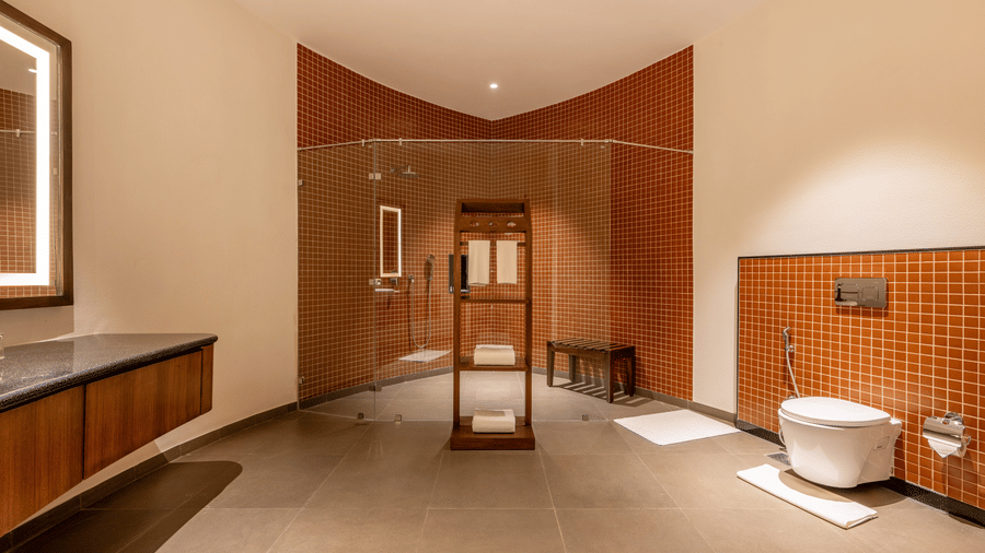 an interior of a bathroom and a shower area separated by glass doors at Ananta Spa and Resort, Ajabgarh