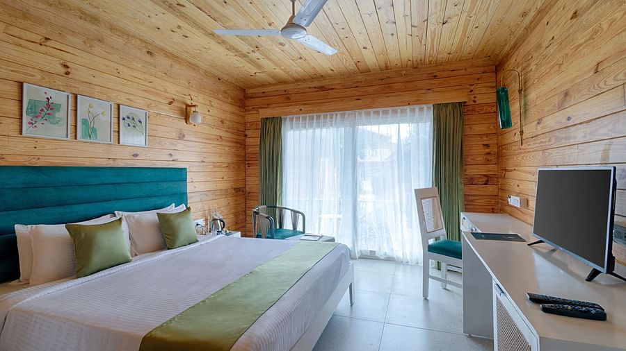 A rustic-chic bedroom with wooden walls, a teal headboard, and a green throw over the bed Aralea Beach Resort by Stone Wood, Morjim