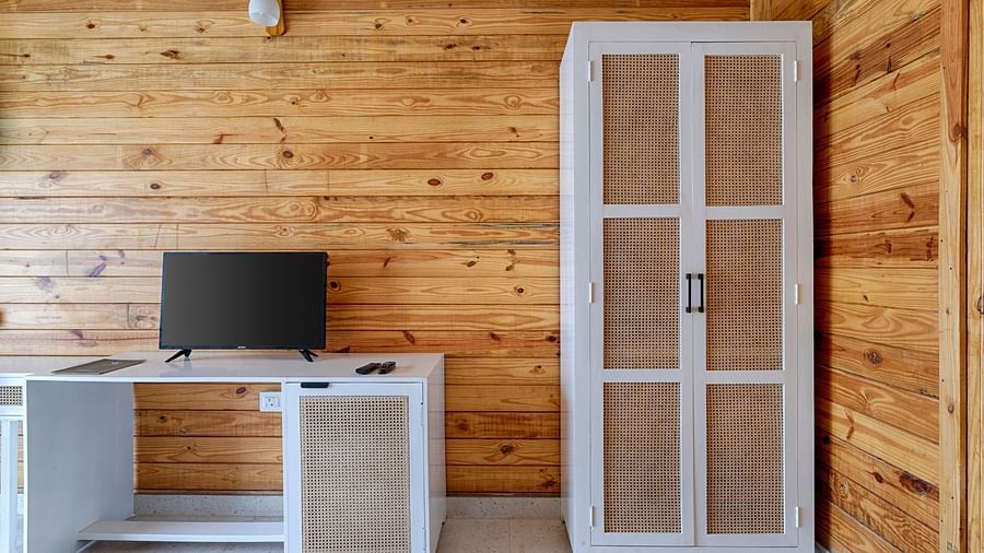 A minimalist bedroom with wooden walls, a white wardrobe, and a large TV Aralea Beach Resort by Stone Wood, Morjim