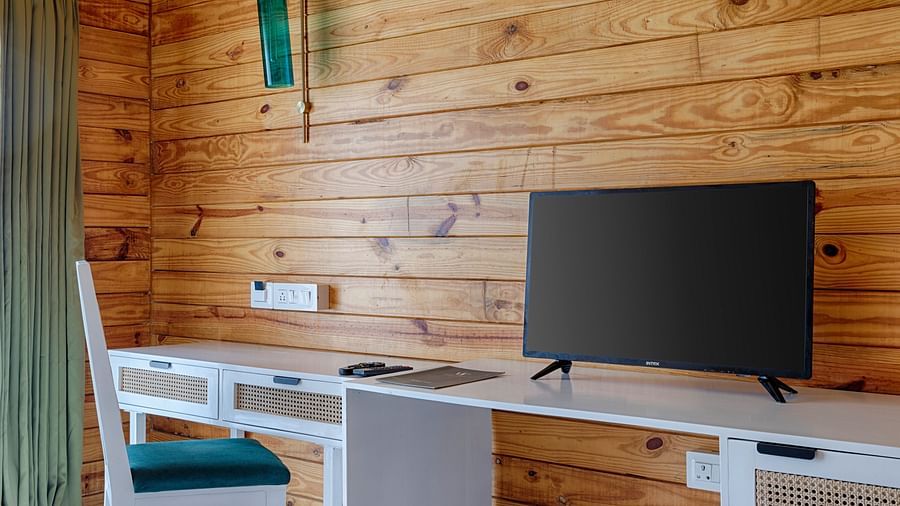 A well-lit bedroom workspace with a large TV, simple furniture, and wooden walls, offering a comfortable and functional space Aralea Beach Resort by Stone Wood, Morjim
