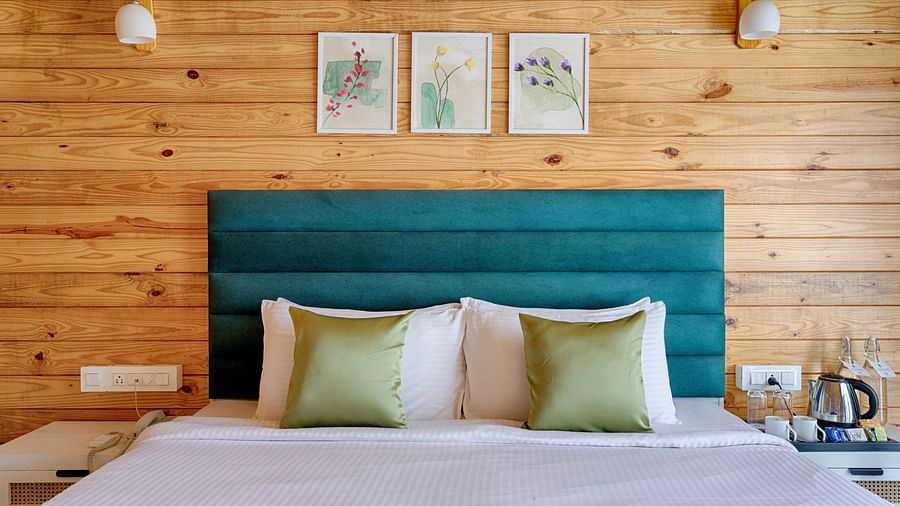 A simple yet stylish bedroom with a plush bed, teal headboard, green accents, and wooden walls, creating a serene space Aralea Beach Resort by Stone Wood, Morjim