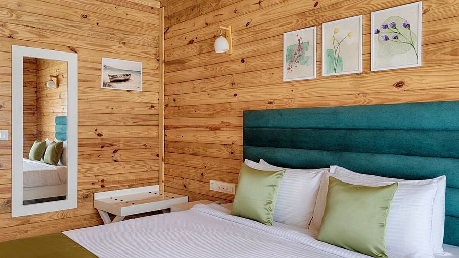 A bright bedroom with a large bed, teal headboard, green accents, and wooden walls, adorned with framed artwork and a reflective mirror Aralea Beach Resort by Stone Wood, Morjim