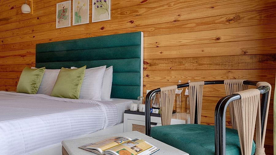 A close-up of the bed showing the green accent pillows and framed botanical prints on the wall Aralea Beach Resort by Stone Wood, Morjim