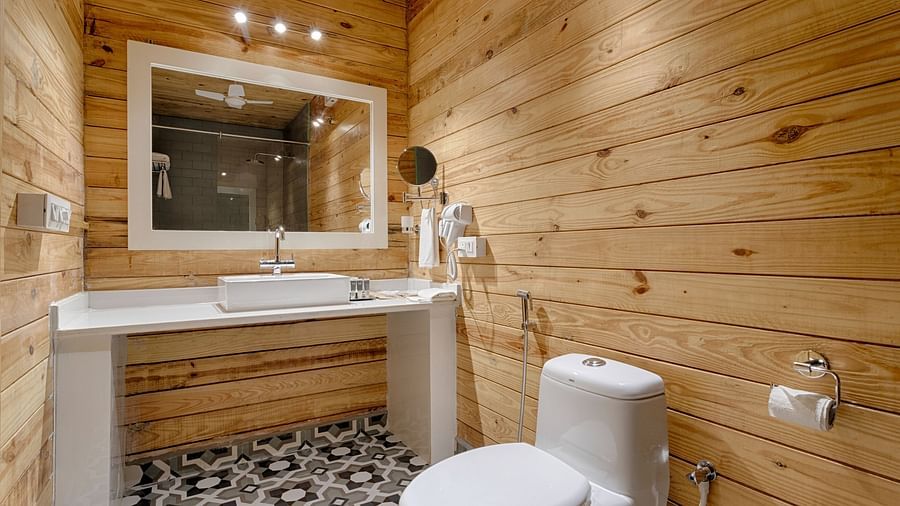 A modern bathroom with wooden walls, white fixtures, a large mirror, and a patterned tile floor giving it a contemporary rustic feel Aralea Beach Resort by Stone Wood, Morjim