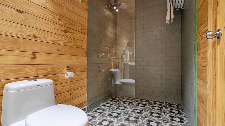A small bathroom featuring a glass shower, white toilet, and wooden walls, with a patterned tile floor adding character Aralea Beach Resort by Stone Wood, Morjim