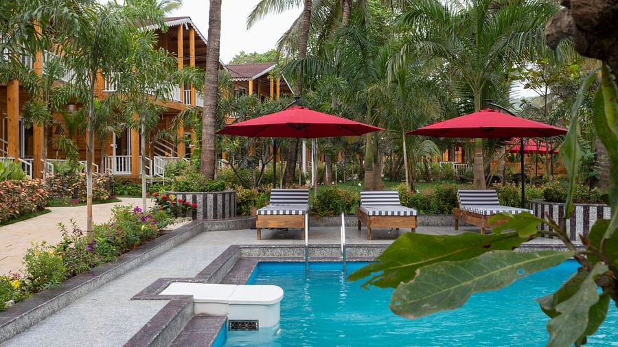 Resort pool with red umbrellas and loungers, tropical cabins in the background Aralea Beach Resort by Stone Wood, Morjim
