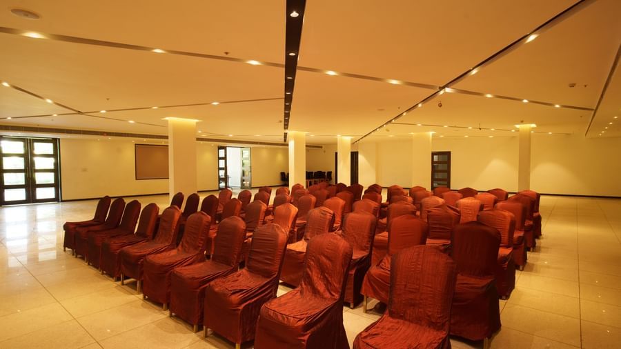 Large banquet or conference hall set up with rows of red chairs for an event at Arawali Ananta Elite, Jaipur.