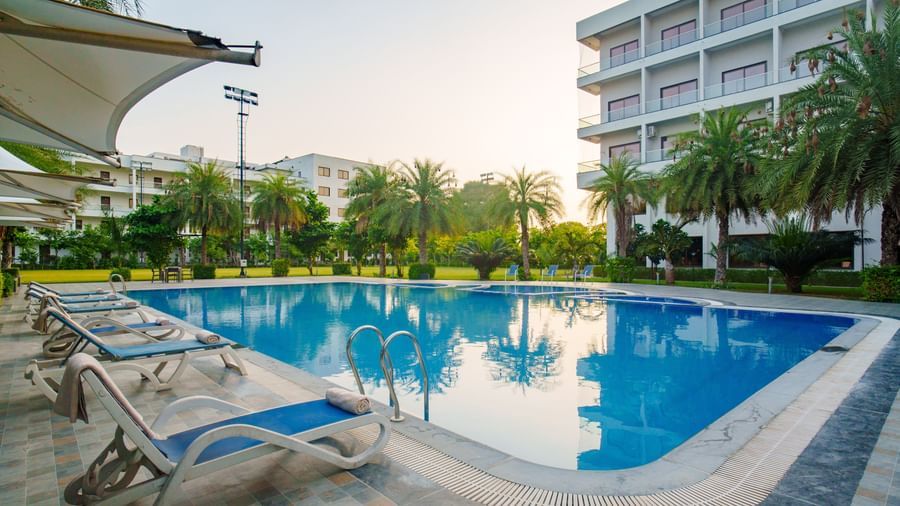 Swimming pool area with the hotel building visible in the background at Arawali Ananta Elite, Jaipur.