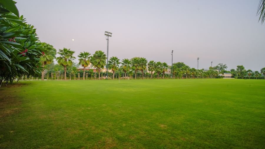 Large outdoor  field covered in grass, visible under a twilight sky at Arawali Ananta Elite, Jaipur.