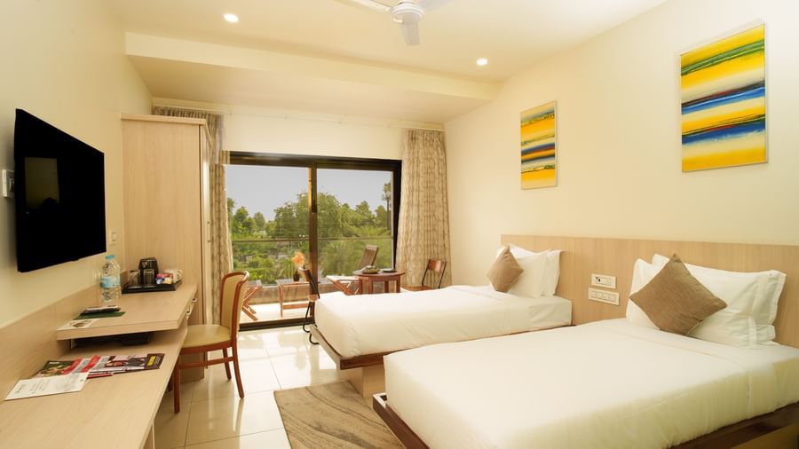 Suite interior showing a bed and a separate seating area with a television and a view of the outdoors at Arawali Ananta Elite, Jaipur.