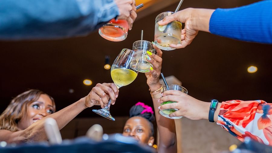 People cry cheers while clicking their drinks' glasses at a party at Asiatic Lounge in Kenya