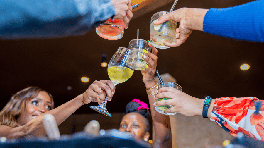 People cry cheers while clicking their drinks' glasses at a party at Asiatic Rooftop Bar and Restaurant in Kenya