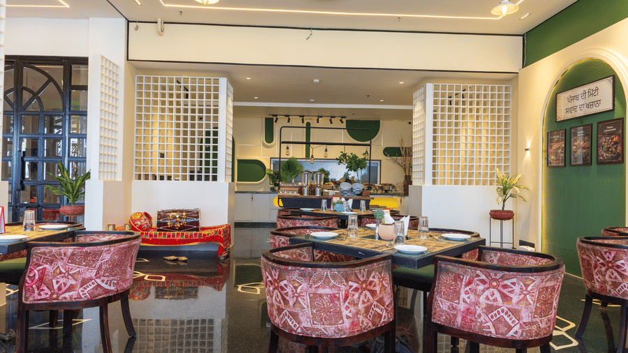 Restaurant interior at Hotel Bawa, Udaipur displaying square dining tables, patterned armchairs, white lattice partitions, and a low seating area.