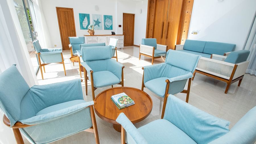 image of the indoor common seating area with pastel blue coloured cushioned chairs around a round coffee table at the beacon by the bay villas and suites in dondra