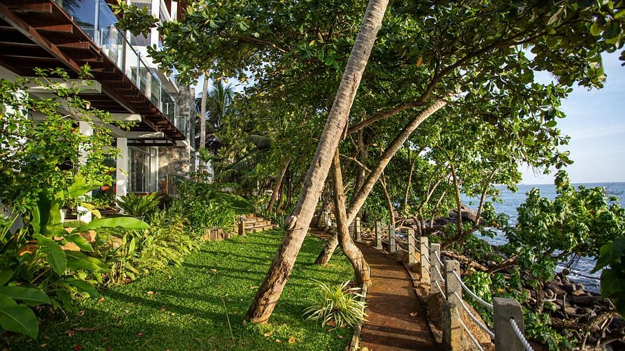 image of a path providing an open uninterrupted view of the sea with a lush green garden on overlooking it at the beacon by the bay villas & suites in dondra