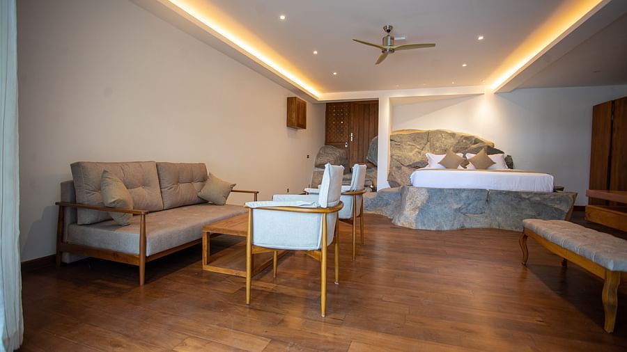 image of the bedroom of the sea view rock suite with a common seating area featuring a beige couch and and a king size bed