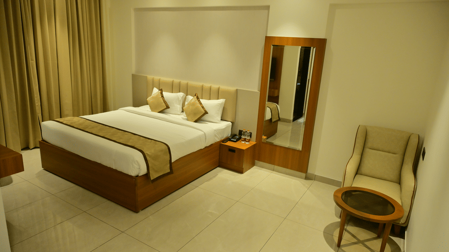 Bedroom of Bhavanis Vista By Icon featuring a bed, a headboard, an armchair, and a mirror.