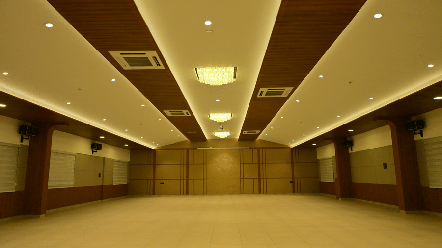 Large event hall at Bhavanis Vista By Icon Hosur with warm recessed lighting, wood-accented ceiling panels, and open floor space.