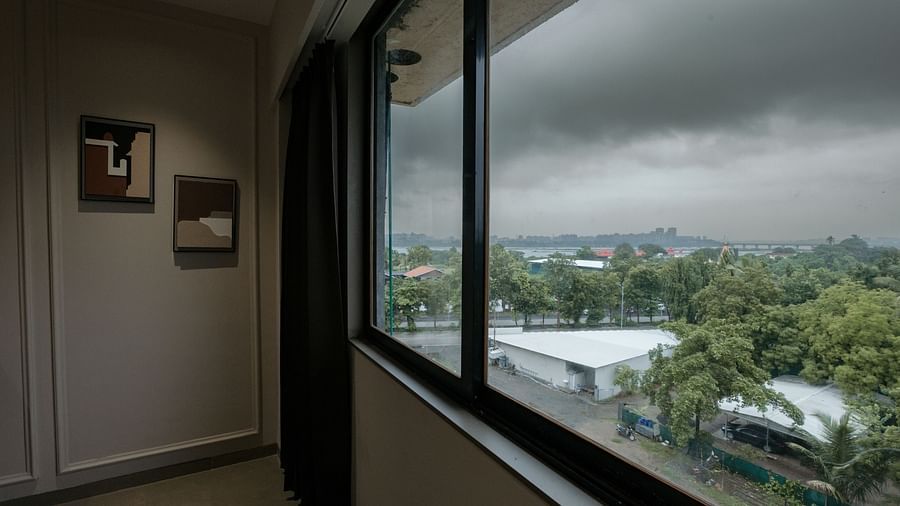 A hotel room's window offering a view of the city and overcast sky - Biznotel By Pride Surat 