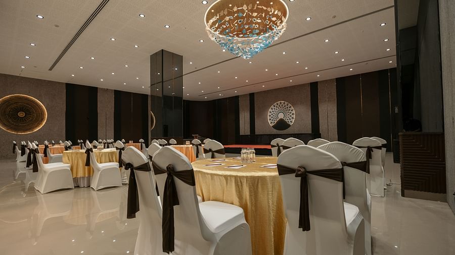 An event space with round tables draped in white, set for a formal function - Biznotel By Pride Surat