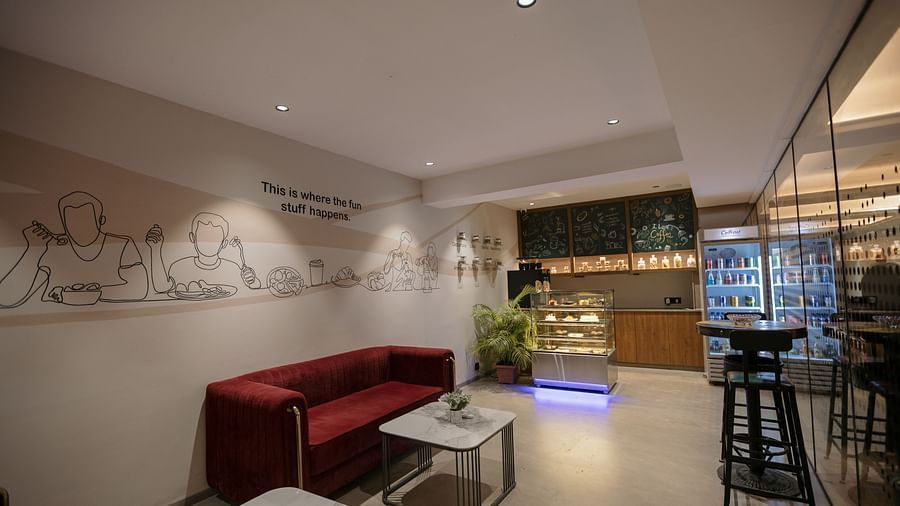 A modern lounge area with a red sofa, tables, and a bar, perfect for casual meetings - Biznotel By Pride Surat