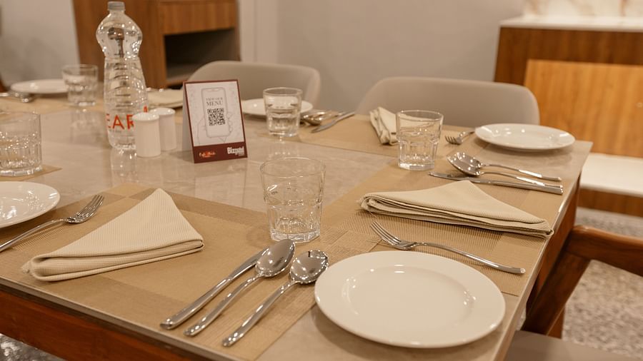 A close-up of a laid dining table with white plates, cutlery, and glassware - Biznotel By Pride Surat
