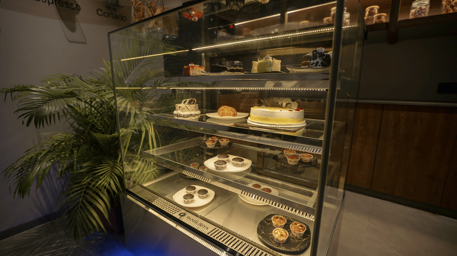 Glass display counter at Biznotel by Pride Surat filled with freshly baked pastries and cakes.