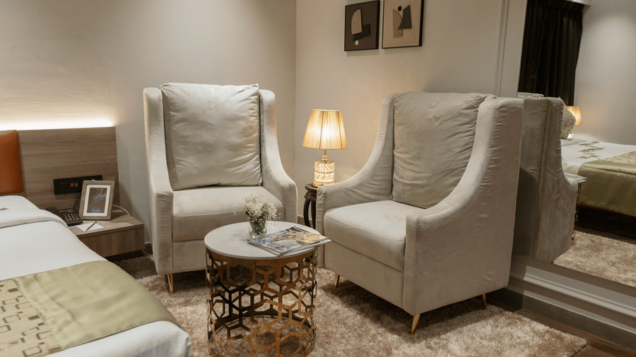 Cosy seating corner inside a room at Biznotel by Pride Surat with plush wingback chairs, a coffee table, and warm lighting.
