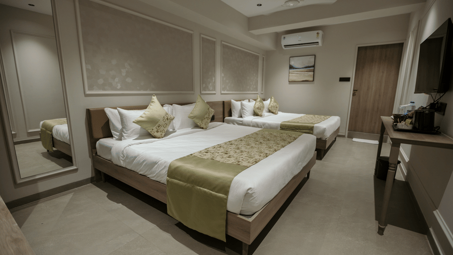 Modern twin bedroom at Biznotel by Pride Surat featuring two double beds, wall molding, and air-conditioning.