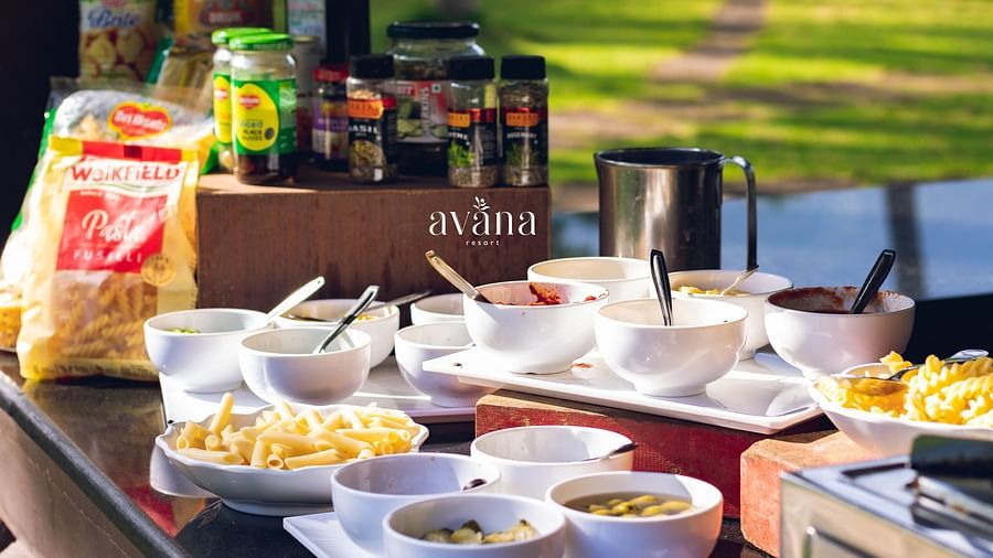 Outdoor buffet setup with bowls of pasta, sauces, and condiments arranged neatly for a live pasta station.