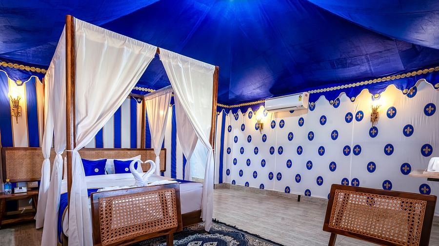 Decorated tent at Buena Vista Luxury Garden Spa Resort with a four-poster bed, blue and white striped walls, and comfortable seating.
