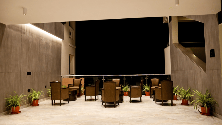 A seating area with tables and chairs with pots on the side at  Amara Grand Baga, Goa.