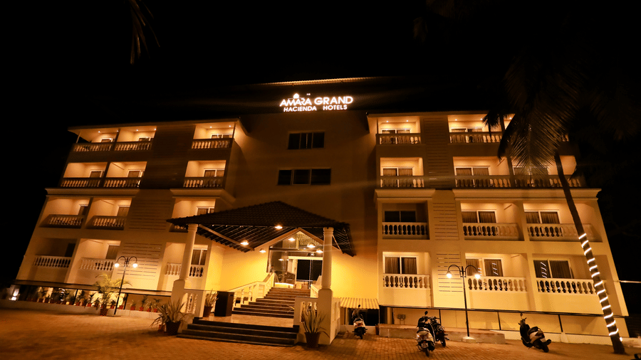 Exterior view of a multi-storey building with Amara Grand, Hacienda Hotels written on top under a night sky.