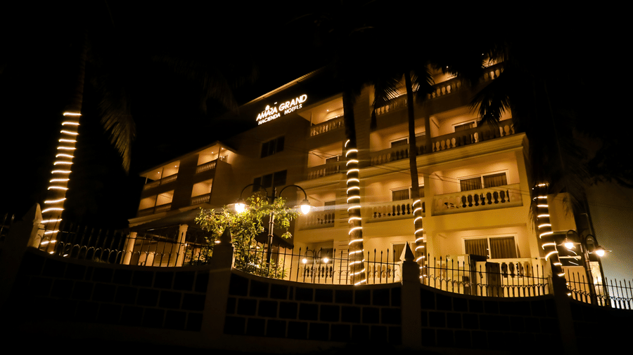 Night view of Amara Grand Baga, Goa's facade surrounded by trees decorated with lights.