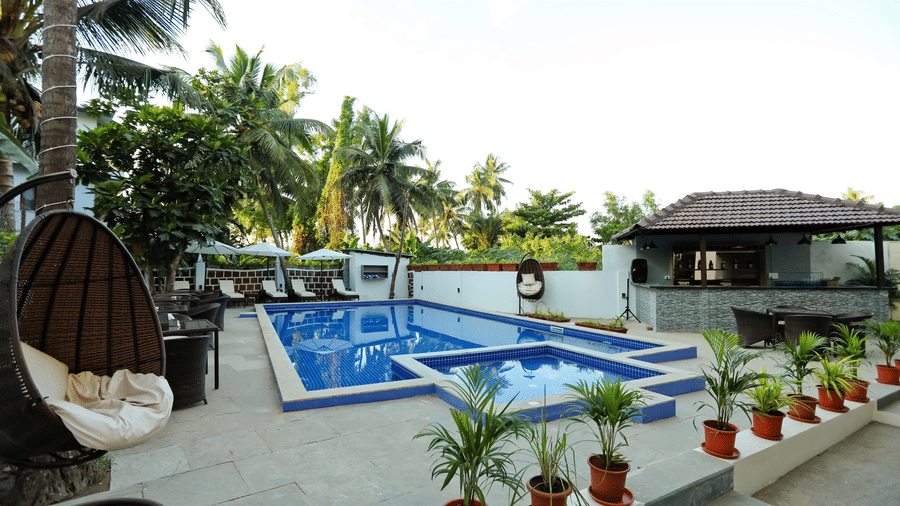 Pots of plants lined beside a swimming pool and a swing on the side at Amara Grand Baga, Goa.