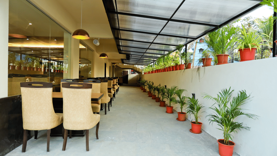 Back view of a dining area with tables and chairs and pots of plants on the side at Amara Grand Baga, Goa.