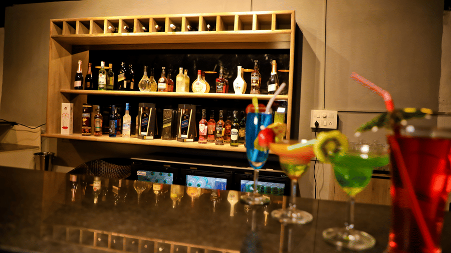 A bar counter with drinks on the counter table and drinks placed in a shelf behind at Amara Grand Baga, Goa.