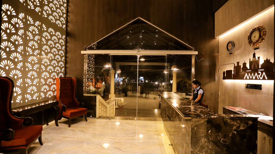 Reception area with a seating area on the side and a reception table opposite to it at Amara Grand Baga, Goa.
