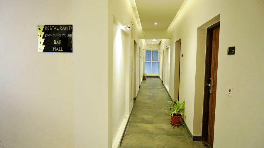 Hallway with doors on the side with a pot of plant outside a door at Amara Grand Baga, Goa.